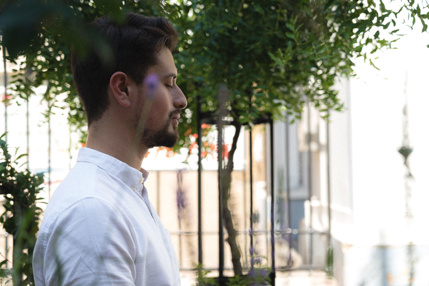 Man meditating outdoors in the sunshine with trees
